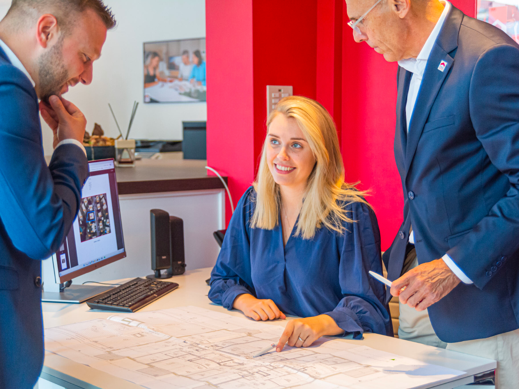 Estate agents with a building plan at a desk.
