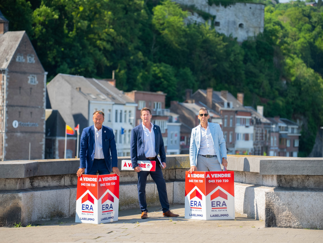 Trois agents immobilier ERA avec panneaux ERA à vendre.