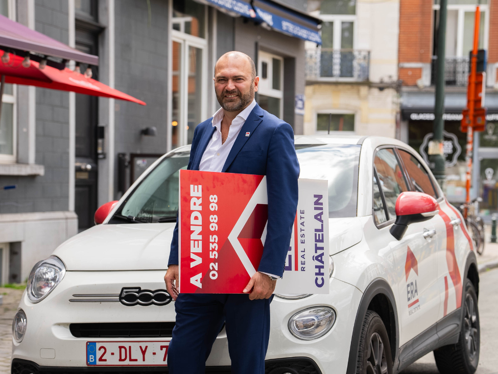 Agent immobilier avec un panneau devant une voiture ERA.