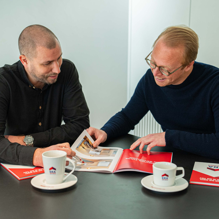 Twee mannen bekijken samen een brochure.