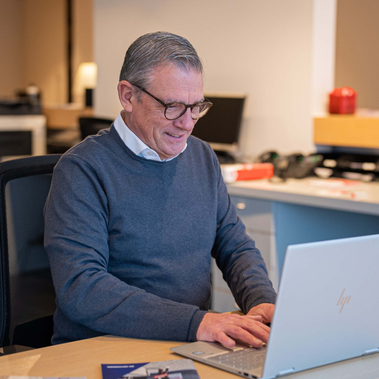 Een oudere man werkt op de computer.