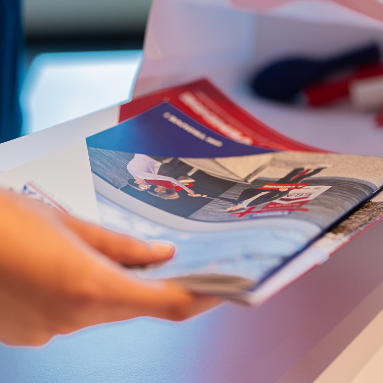 Een persoon vult een goodiebag met ERA Open Huizen Dag materiaal.