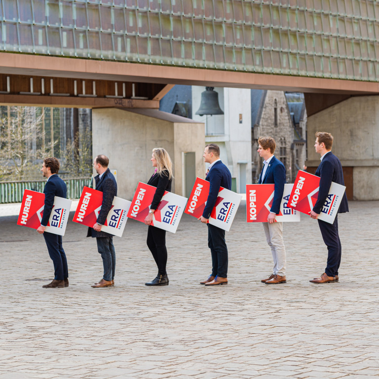 Verschillende ERA makelaars staan naast mekaar met elks een ERA V-Bord in hun handen.