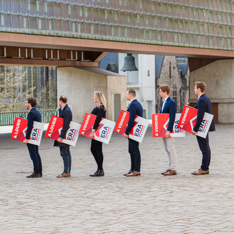 Plusieurs agents immobiliers ERA se tiennent les uns à côté des autres, chacun tenant un panneau ERA