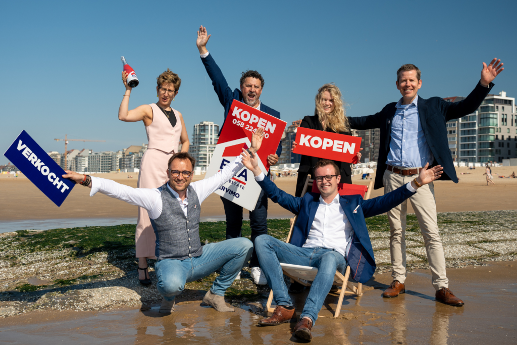 Makelaars lachend aan de kust met v-borden.