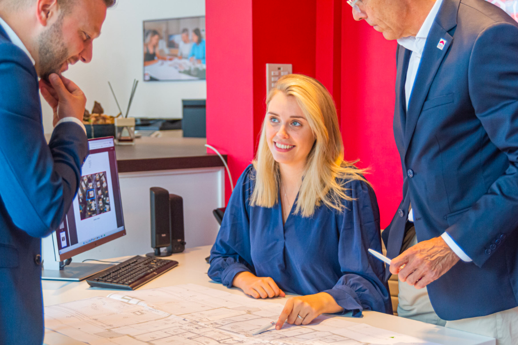 Makelaars met een bouwplan aan een bureau.