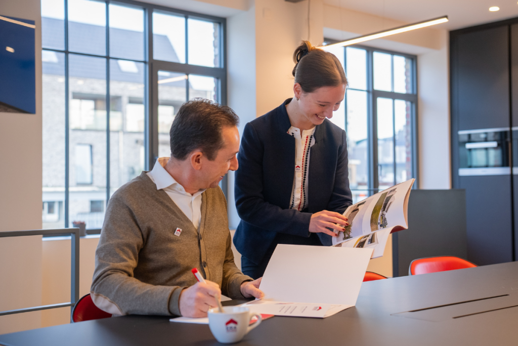 Twee ERA makelaars samen naar een brochure aan het kijken.