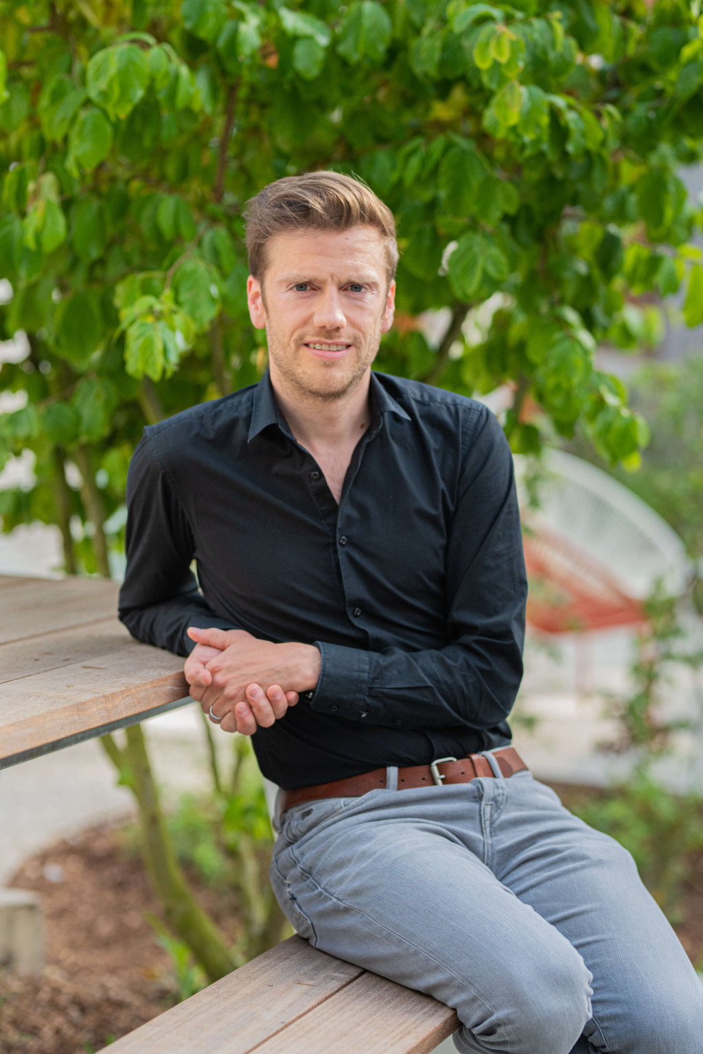 Topmakelaar Johan zit op een bankje.