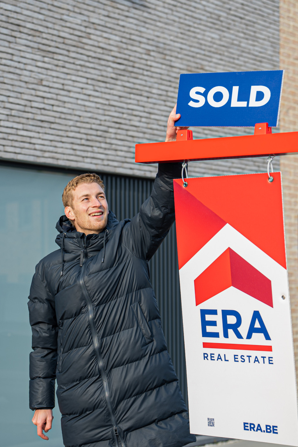 A man puts a sticker, with the word sold on an ERA billboard.