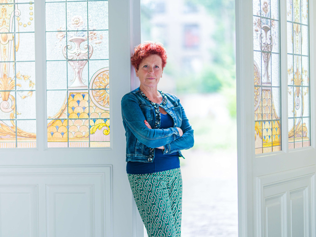 Topmakelaar Béa staat in een deuropening.