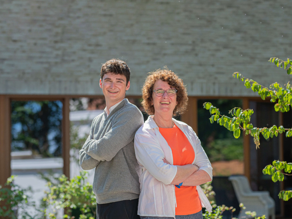Topmakelaars Dorine en Matthew lachen naar de camera terwijl ze rug tegen rug in de zon staan.
