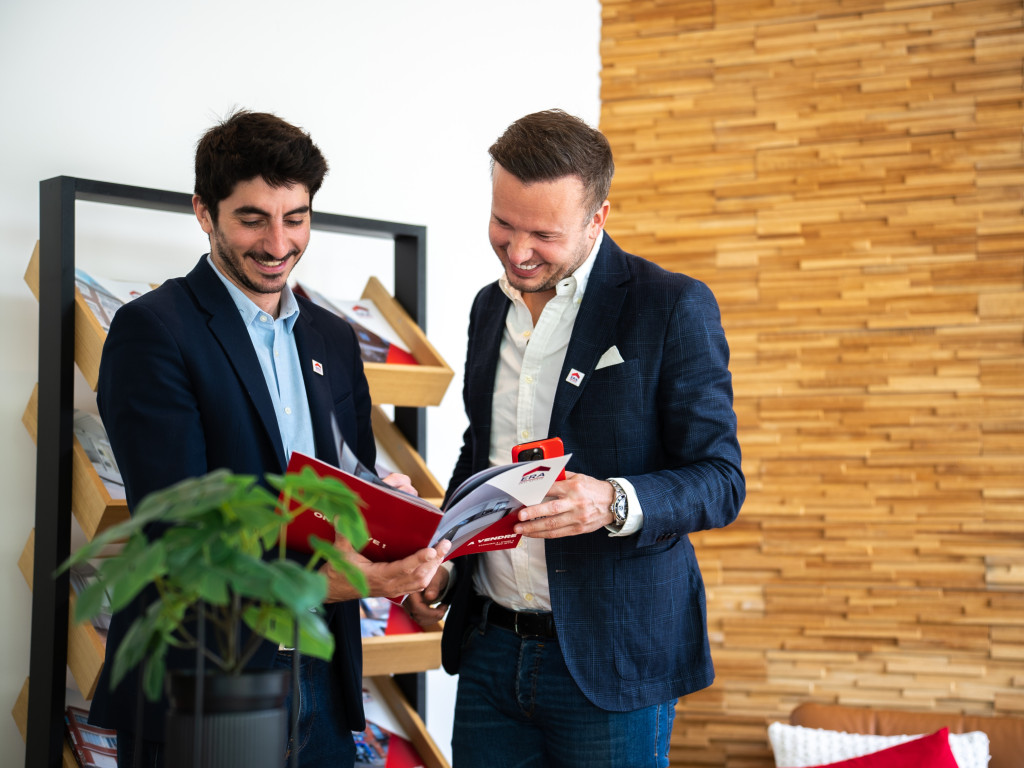 Makelaars die lachend kijken naar een luxebrochure.