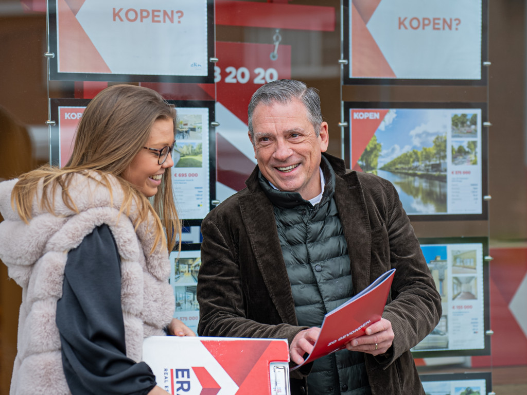 Makelaars lachend voor een etalage.