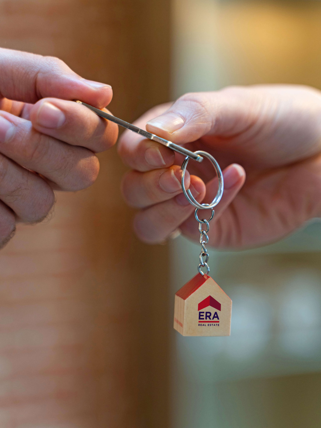 Een persoon geeft een sleutel met een ERA sleutelhanger door aan iemand anders.
